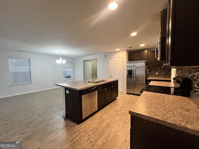 kitchen featuring sink, pendant lighting, a kitchen island with sink, appliances with stainless steel finishes, and light wood-type flooring