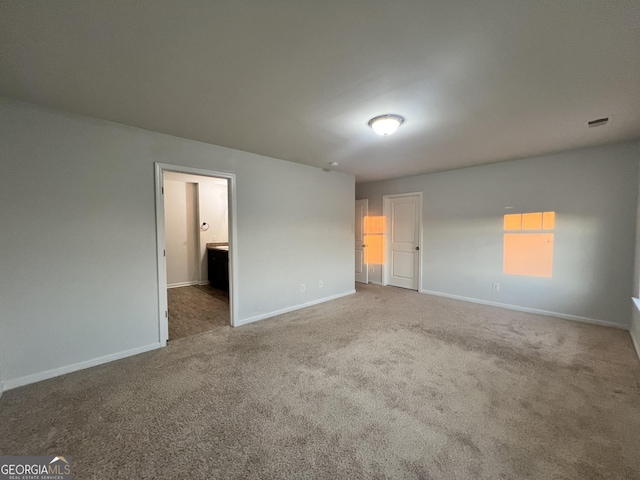 unfurnished bedroom with connected bathroom and carpet floors