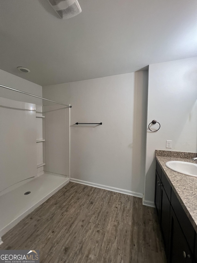 bathroom featuring hardwood / wood-style floors, vanity, and walk in shower