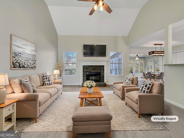 living room with ceiling fan, a stone fireplace, and high vaulted ceiling