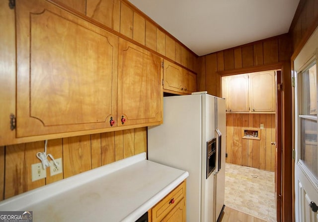 kitchen with white refrigerator with ice dispenser and wooden walls