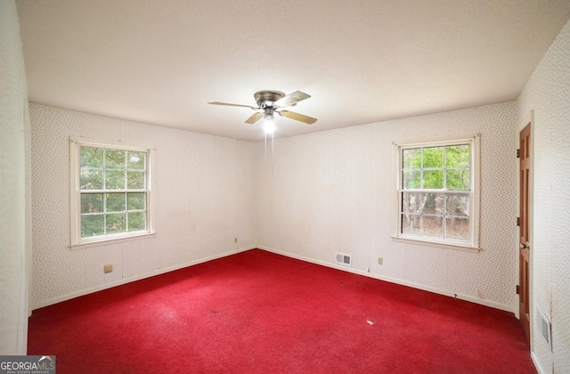 carpeted spare room featuring a wealth of natural light and ceiling fan