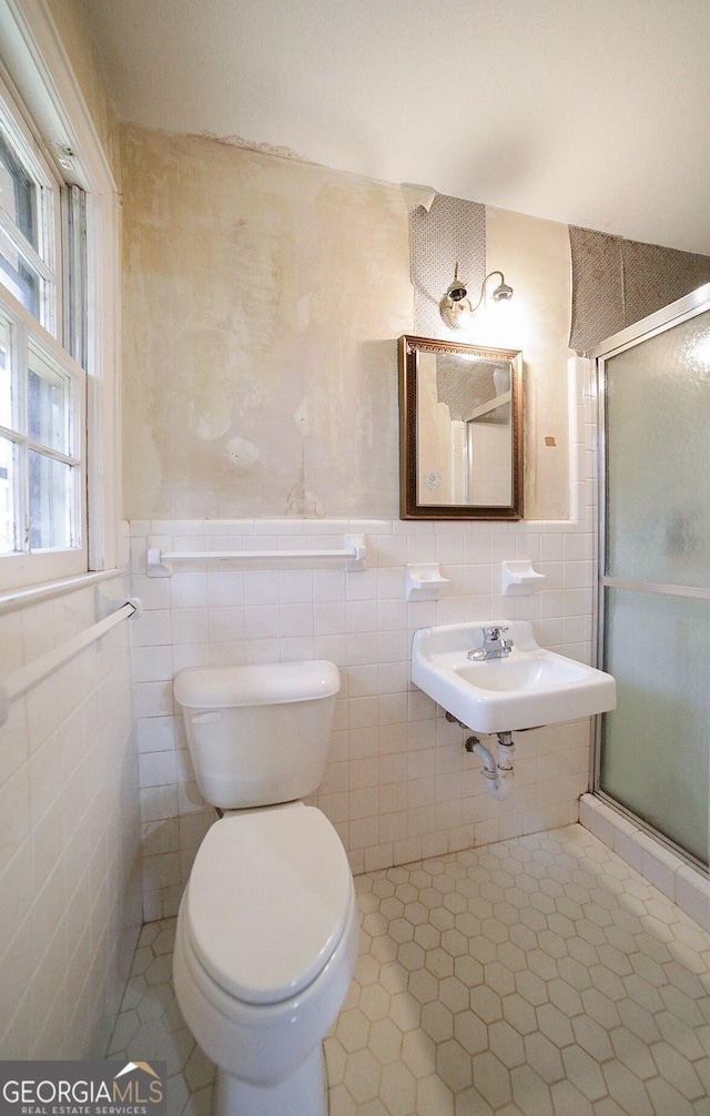 bathroom featuring sink, a shower with door, and tile walls