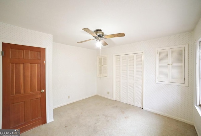 unfurnished bedroom with light carpet, ceiling fan, and multiple closets