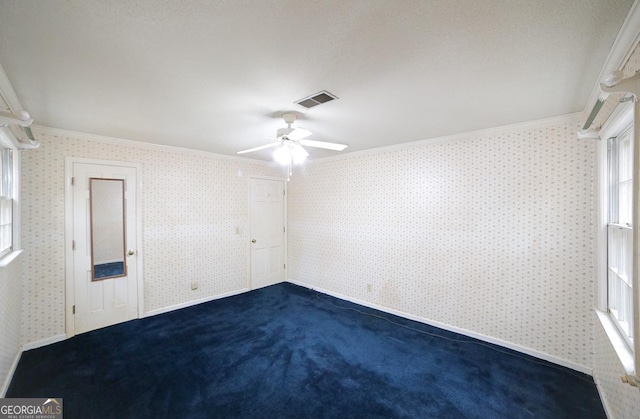 spare room with dark carpet, ceiling fan, and crown molding