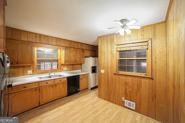 kitchen featuring wooden walls, sink, black dishwasher, light hardwood / wood-style floors, and white fridge with ice dispenser