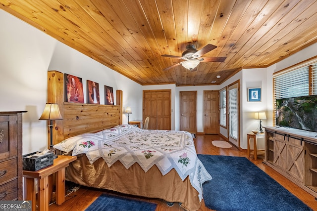 bedroom featuring wooden ceiling, ceiling fan, wood-type flooring, and multiple closets