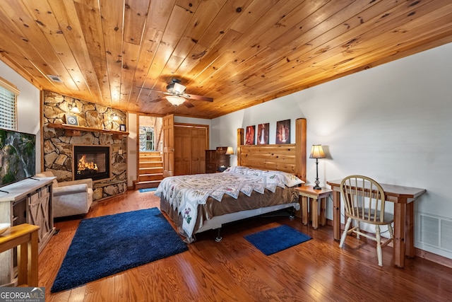 bedroom with a fireplace, ceiling fan, hardwood / wood-style floors, and wood ceiling