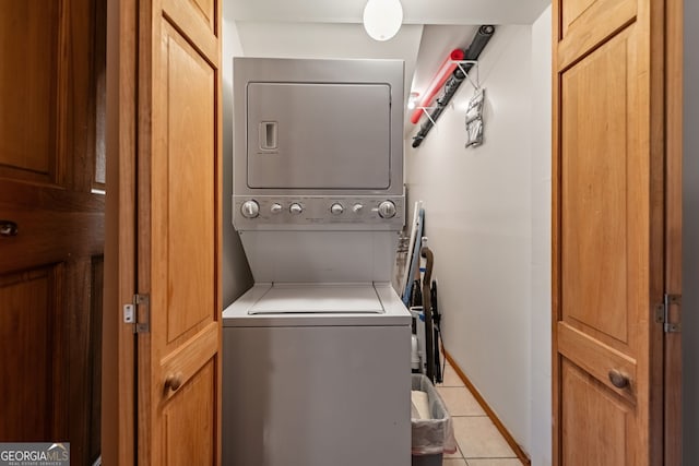 laundry area with light tile patterned floors and stacked washing maching and dryer