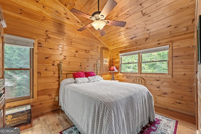 bedroom featuring light hardwood / wood-style flooring, multiple windows, and wood walls