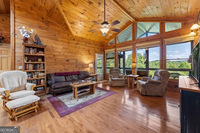 living room featuring ceiling fan, beamed ceiling, wood walls, wood ceiling, and hardwood / wood-style flooring