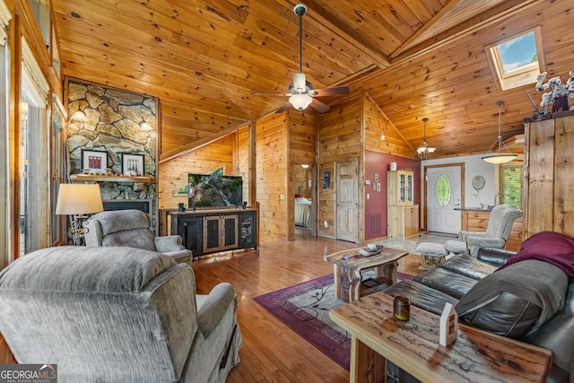 living room featuring a skylight, ceiling fan, hardwood / wood-style floors, wooden walls, and wood ceiling