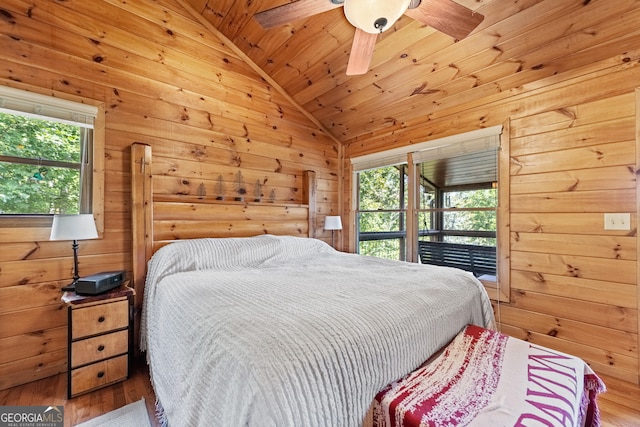 bedroom featuring hardwood / wood-style floors, wood walls, and vaulted ceiling