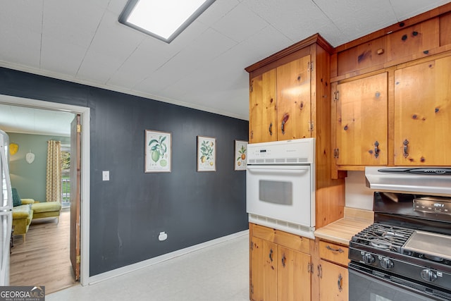 kitchen featuring light wood-type flooring, black gas stove, white oven, and crown molding