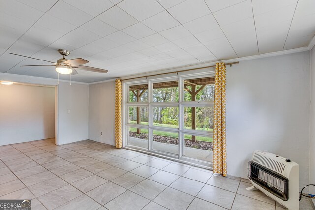 spare room with heating unit, ceiling fan, crown molding, and light tile patterned flooring