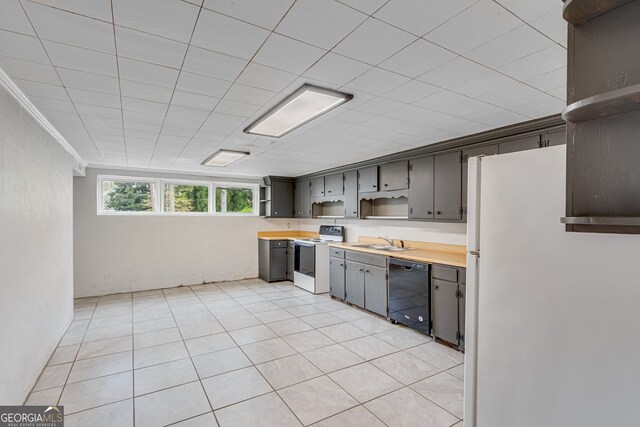 kitchen with sink, light tile patterned floors, white appliances, and wood counters