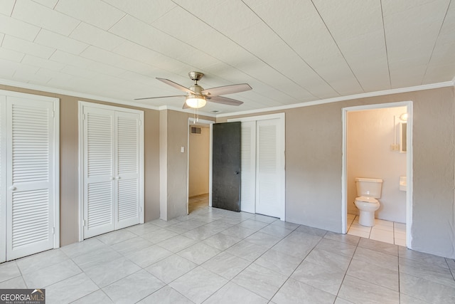 unfurnished bedroom with connected bathroom, ceiling fan, multiple closets, light tile patterned floors, and ornamental molding