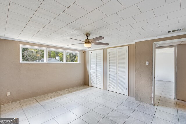 unfurnished bedroom featuring ceiling fan, light tile patterned flooring, and two closets