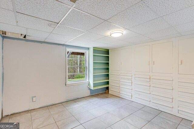 basement featuring a paneled ceiling and light tile patterned floors