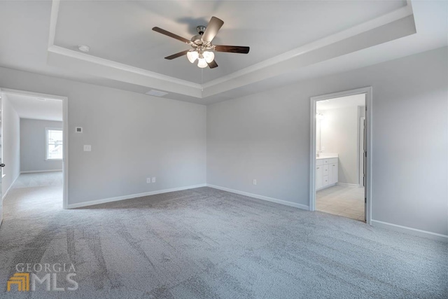 spare room featuring ceiling fan, a tray ceiling, and light colored carpet