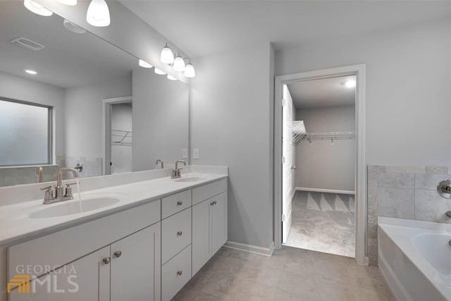 bathroom with tile patterned floors, a bathing tub, and vanity