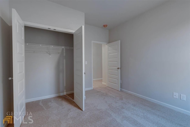 unfurnished bedroom featuring light colored carpet and a closet