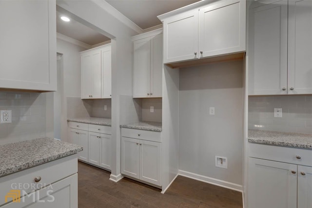 kitchen with backsplash, light stone counters, white cabinetry, crown molding, and dark hardwood / wood-style flooring