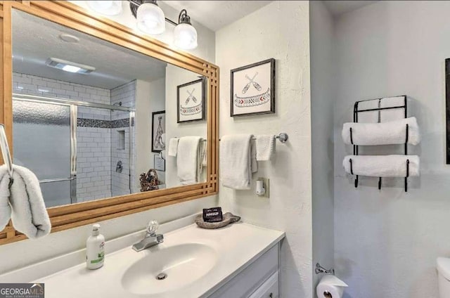 bathroom featuring a shower with door and vanity