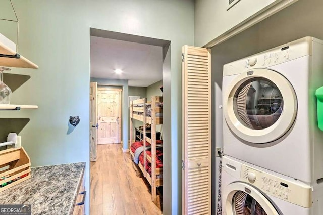 laundry area featuring light hardwood / wood-style flooring and stacked washer / drying machine