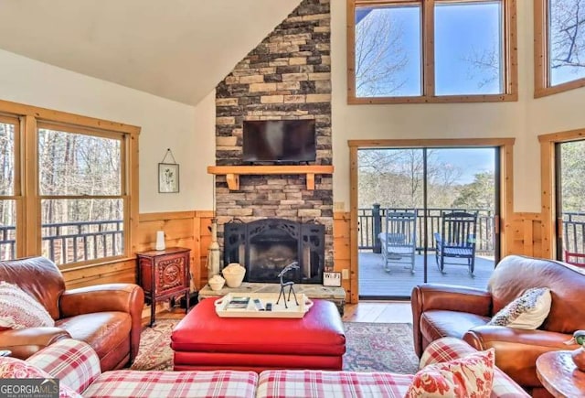 living room featuring hardwood / wood-style flooring, wooden walls, a stone fireplace, and high vaulted ceiling