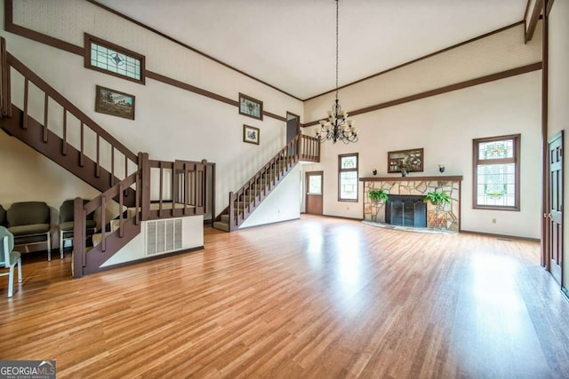 living room with a fireplace, a towering ceiling, a healthy amount of sunlight, and wood-type flooring