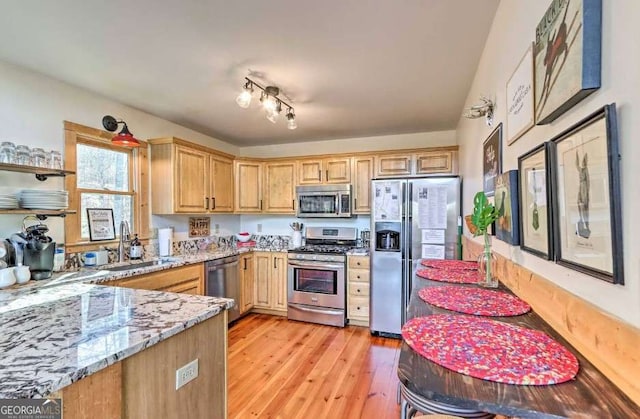 kitchen with track lighting, sink, light hardwood / wood-style flooring, appliances with stainless steel finishes, and light stone counters