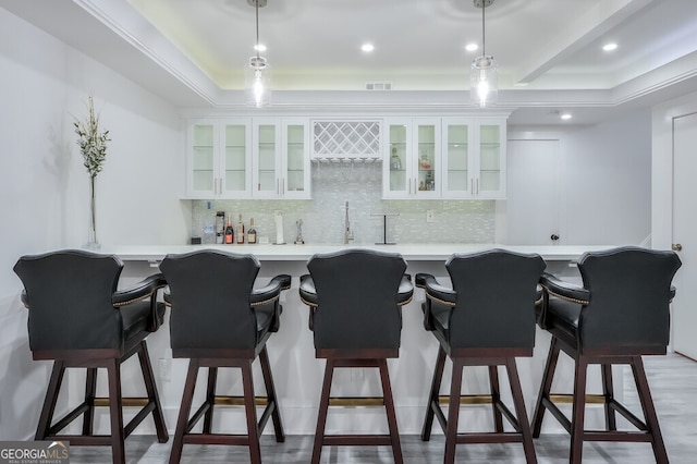 kitchen with decorative backsplash, a kitchen bar, white cabinetry, and kitchen peninsula