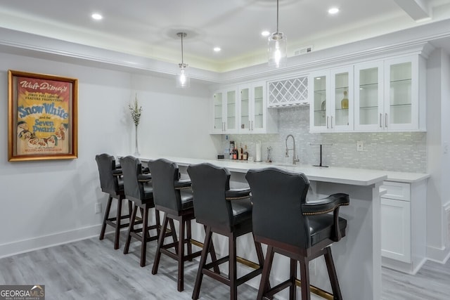 bar with white cabinetry, sink, pendant lighting, decorative backsplash, and light wood-type flooring