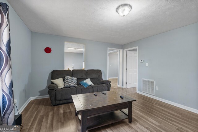 living room with a textured ceiling and dark wood-type flooring