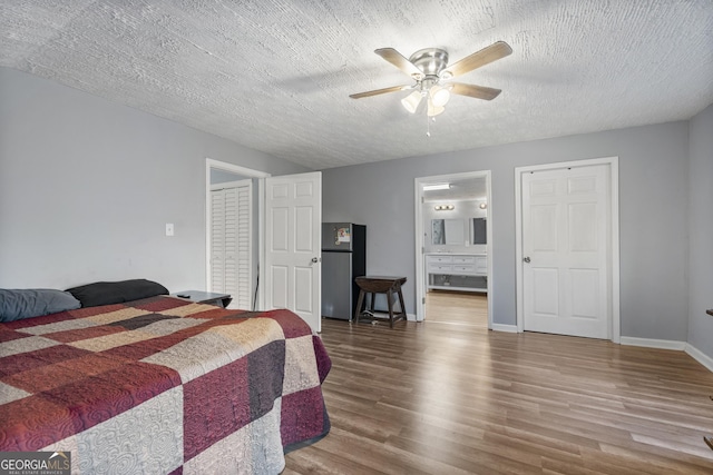 bedroom with stainless steel refrigerator, ceiling fan, wood-type flooring, and a textured ceiling