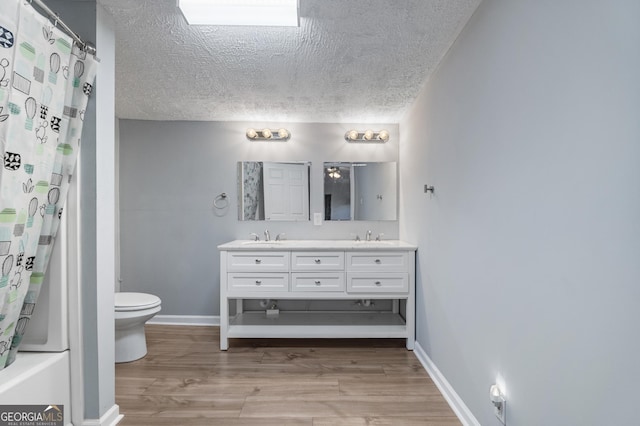 full bathroom with hardwood / wood-style floors, vanity, toilet, a textured ceiling, and shower / tub combo