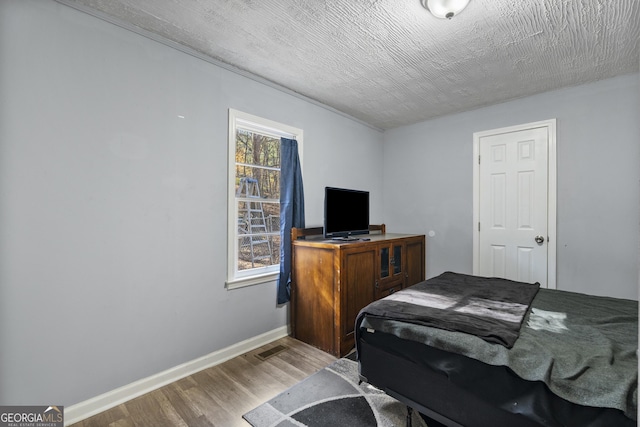 bedroom with hardwood / wood-style floors and a textured ceiling