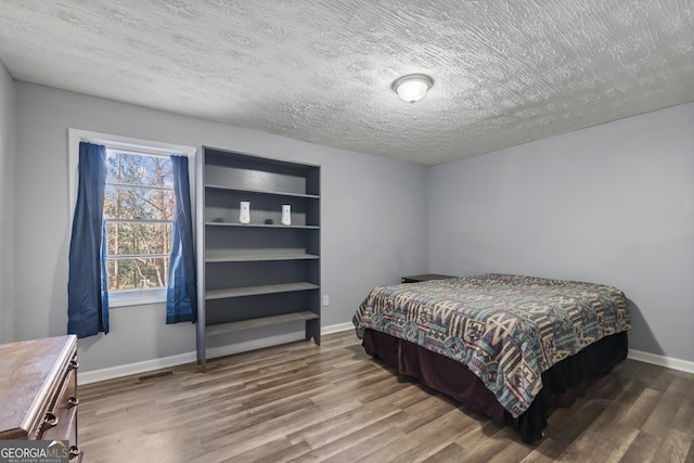 bedroom with wood-type flooring and a textured ceiling