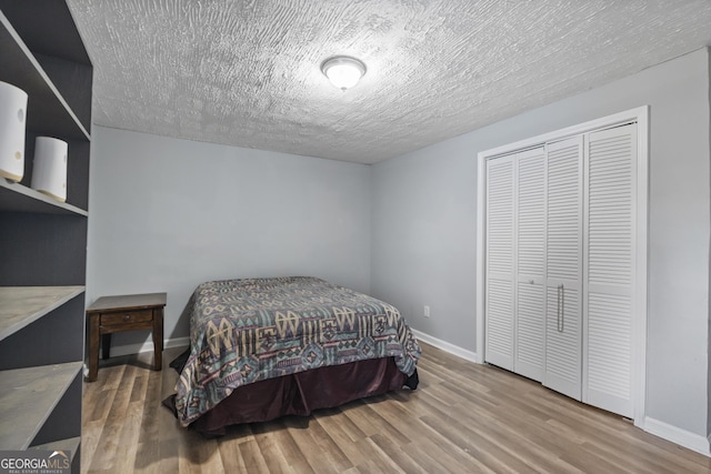 bedroom featuring wood-type flooring, a textured ceiling, and a closet