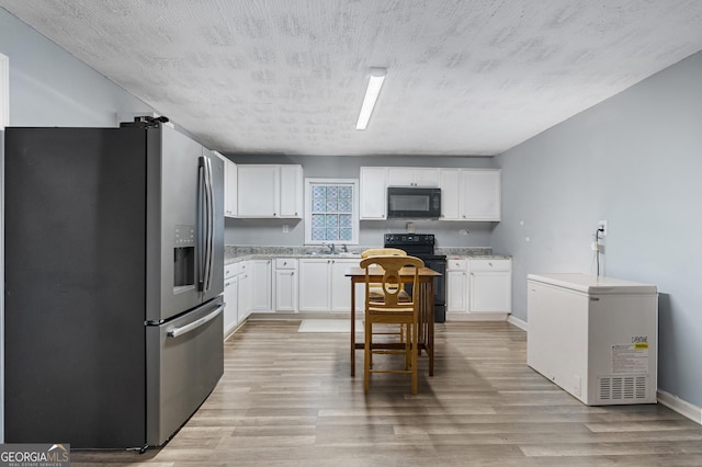 kitchen with white cabinetry, light hardwood / wood-style flooring, black appliances, and a textured ceiling