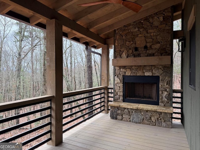 wooden terrace featuring ceiling fan and an outdoor stone fireplace