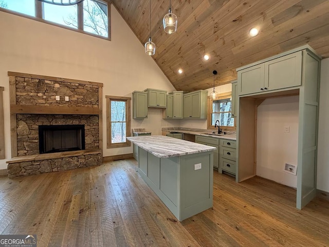 kitchen featuring sink, high vaulted ceiling, green cabinets, pendant lighting, and light stone countertops