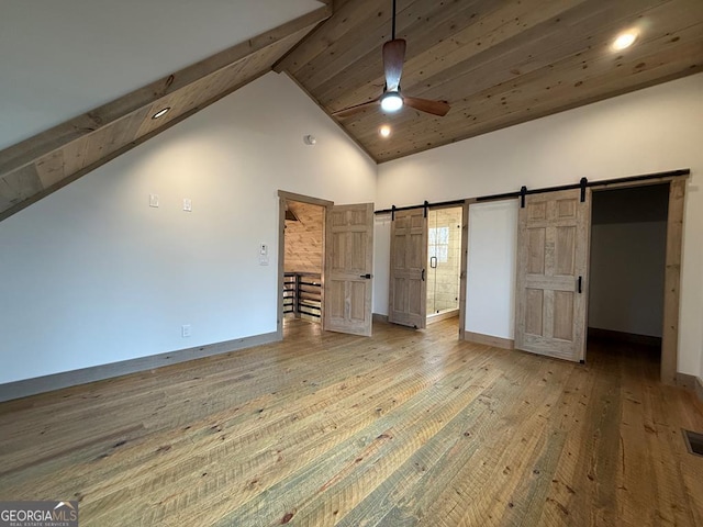 unfurnished bedroom featuring high vaulted ceiling, hardwood / wood-style flooring, ceiling fan, a barn door, and beam ceiling