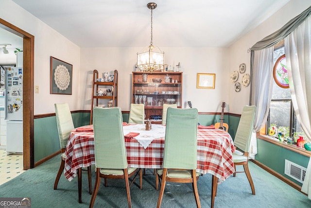 carpeted dining area with a chandelier