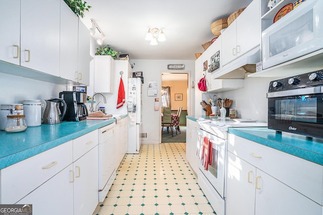 kitchen with white cabinetry, sink, and white appliances