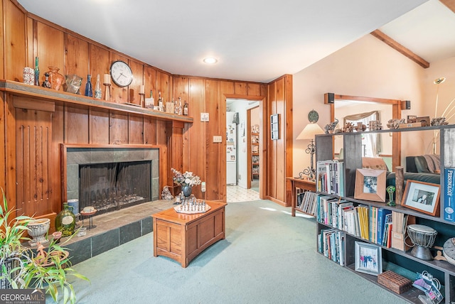 living room featuring carpet flooring, a tiled fireplace, wooden walls, and vaulted ceiling