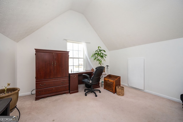 office area featuring lofted ceiling, baseboards, and light carpet