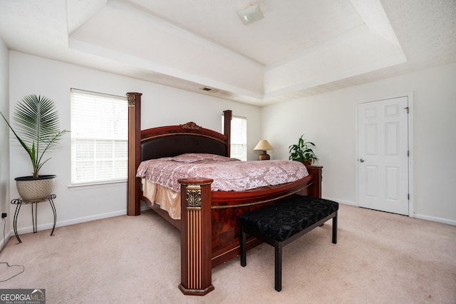 bedroom with a tray ceiling and light colored carpet