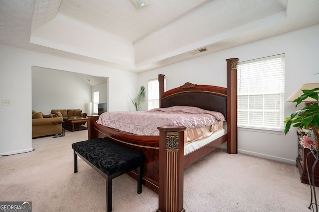 carpeted bedroom featuring a raised ceiling, baseboards, and visible vents